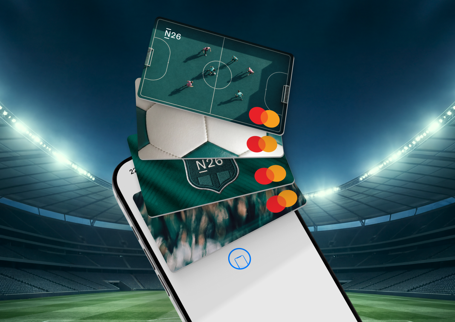 A smartphone screen displays a fan-shaped stack of four N26 Mastercard virtual debit cards with football-themed designs, set against the background of a blurred football stadium.