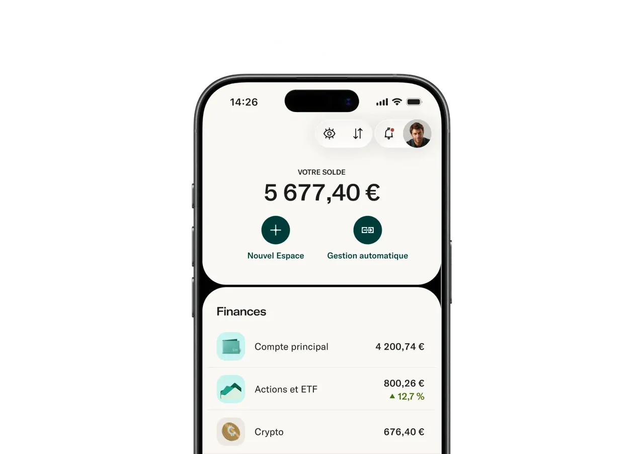 L'écran d'un smartphone affiche l'interface d'une application bancaire indiquant un solde total de 5 677,40 € ainsi que des comptes financiers pour l'épargne principale, les actions et ETF, et les cryptomonnaies.