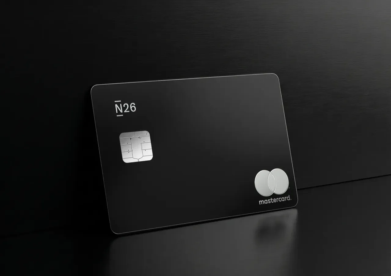 Eine physische schwarze N26 Metal Mastercard steht vor einem dunklen, gebürsteten Metallhintergrund.