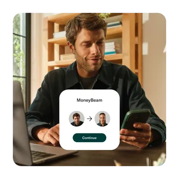 A man looking at his smartphone displays a MoneyBeam overlay showing a money transfer from his profile picture to another user's profile picture.