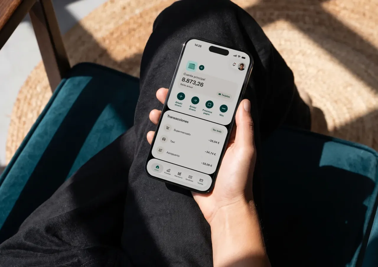 Una persona sostiene un teléfono inteligente que muestra una aplicación de banca móvil con los detalles de la cuenta y las transacciones recientes.