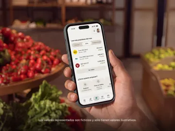 Una mano tiene uno smartphone che mostra opzioni di investimento ed ETF in un'app mobile presso un mercato di prodotti freschi.