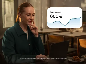 Una mujer está sentada frente a un escritorio con una computadora portátil abierta junto a un gráfico flotante que muestra inversiones de 600 € con una línea de tendencia ascendente.