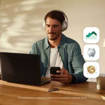 A man wearing headphones looks at his smartphone while sitting at a desk with an open laptop, a credit card, and three icons representing real estate, savings, and cryptocurrency on the right.
